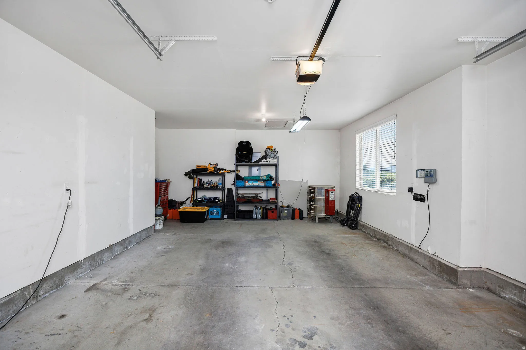 Spacious two-car garage featuring a concrete floor, white painted walls, and a window for natural light