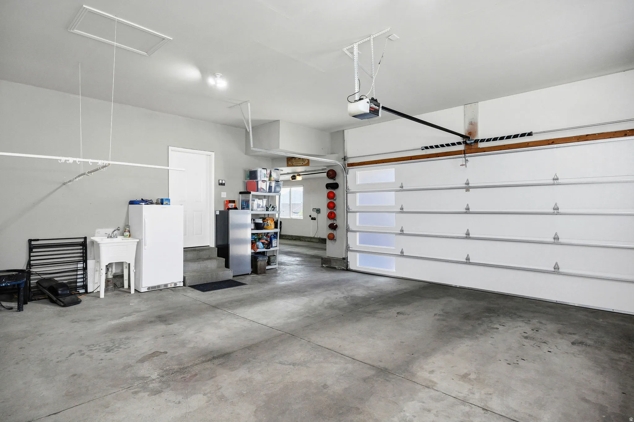 Spacious garage featuring a concrete floor, overhead door with translucent panels, and an automatic garage door opener