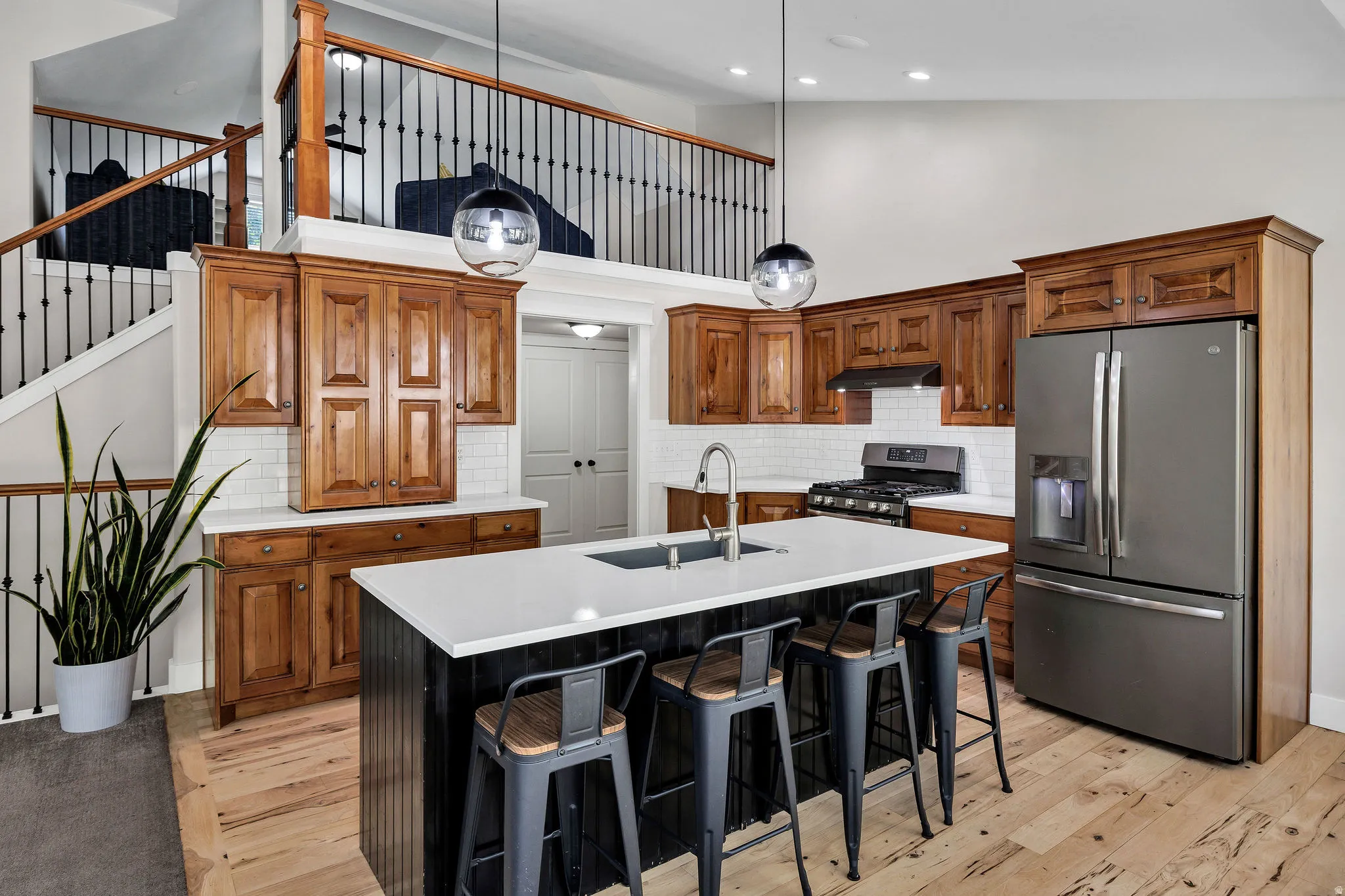 Open-concept kitchen featuring wood-finish cabinetry, white subway tile backsplash, and stainless steel appliances