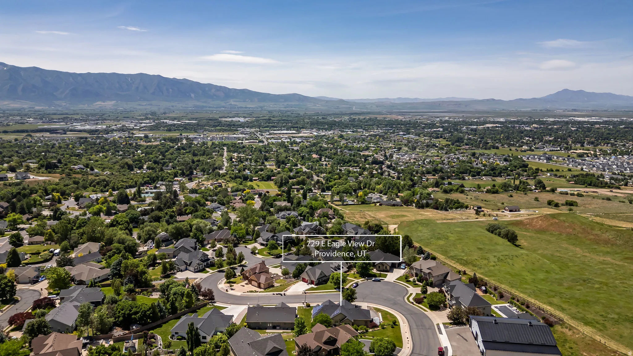 Aerial perspective showcasing a residential neighborhood with surrounding mountains and expansive green spaces
