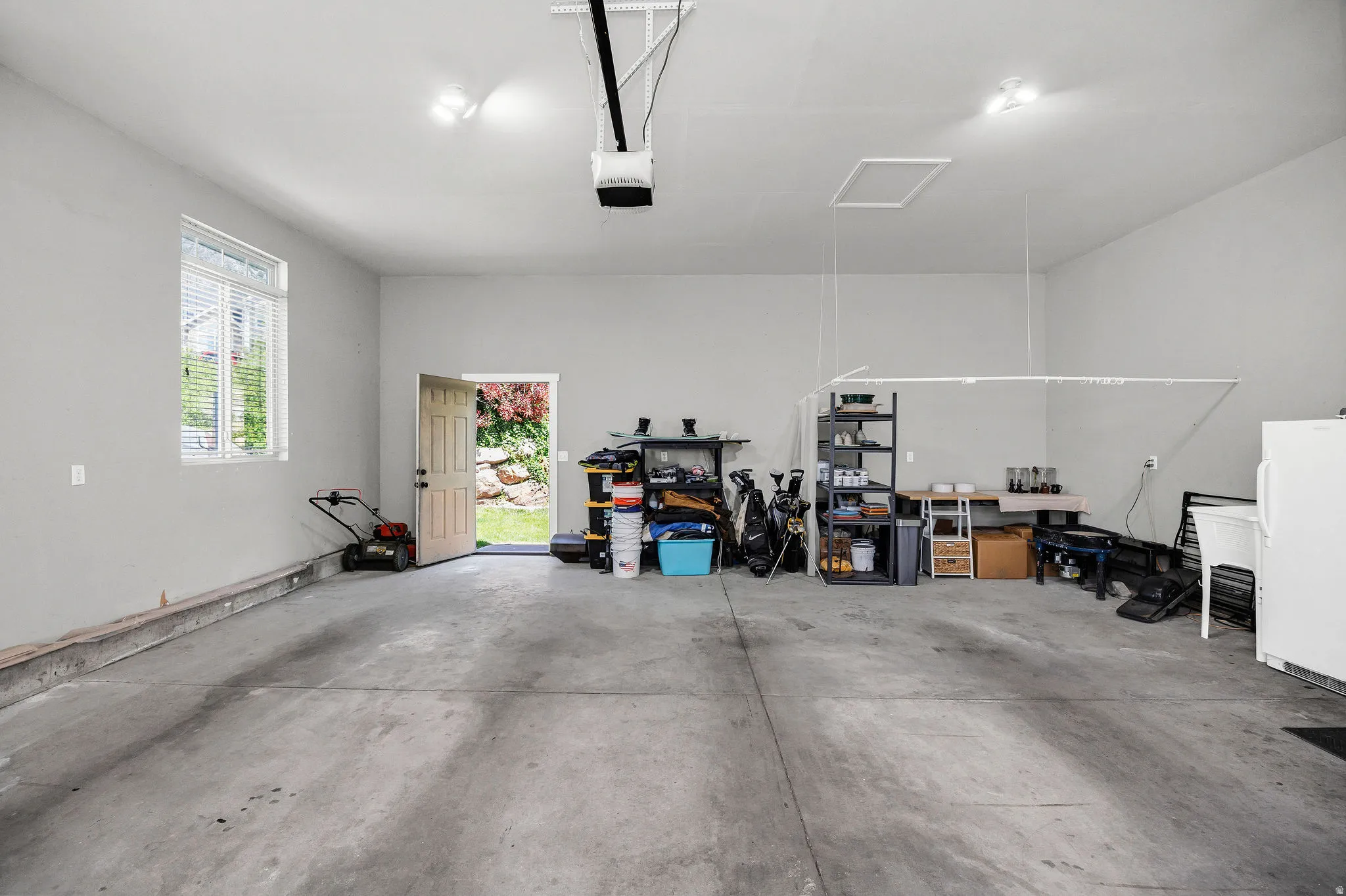 Spacious garage featuring a concrete floor, light gray walls, and a window with blinds