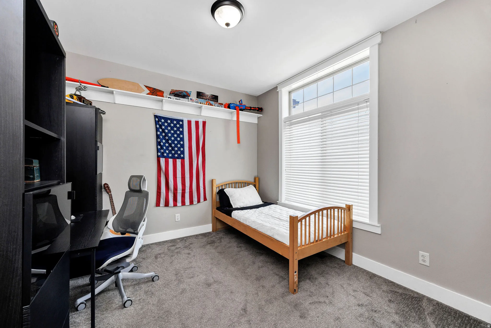 Spacious room featuring neutral grey wall paint, plush grey carpet flooring, and white baseboards