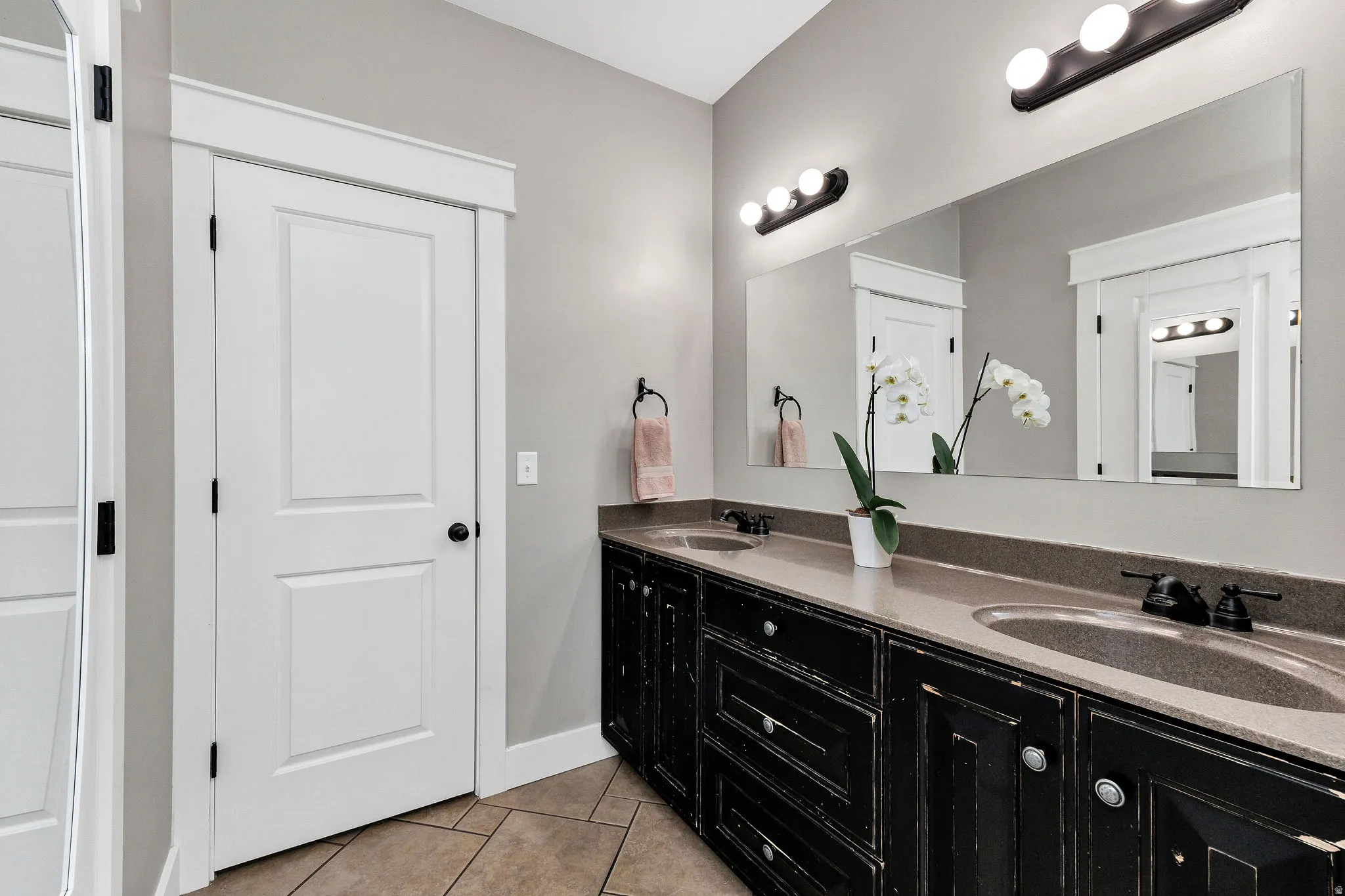 Dual vanity with dark distressed wood-finish cabinetry, integrated sinks, and neutral countertops
