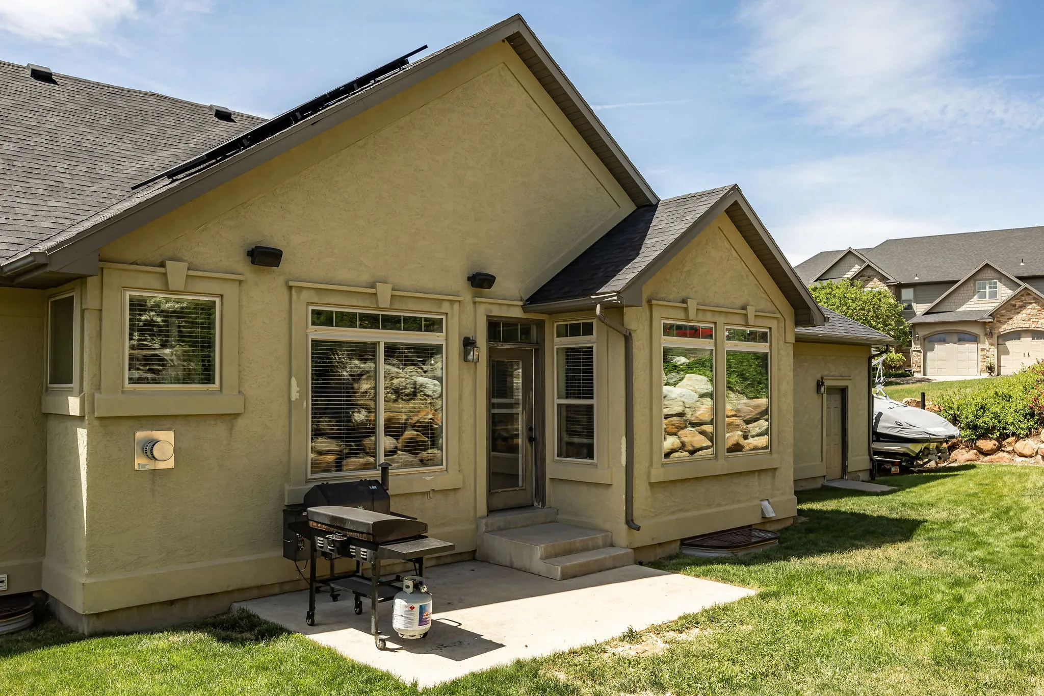 Stucco exterior with multiple windows and a shingled roof