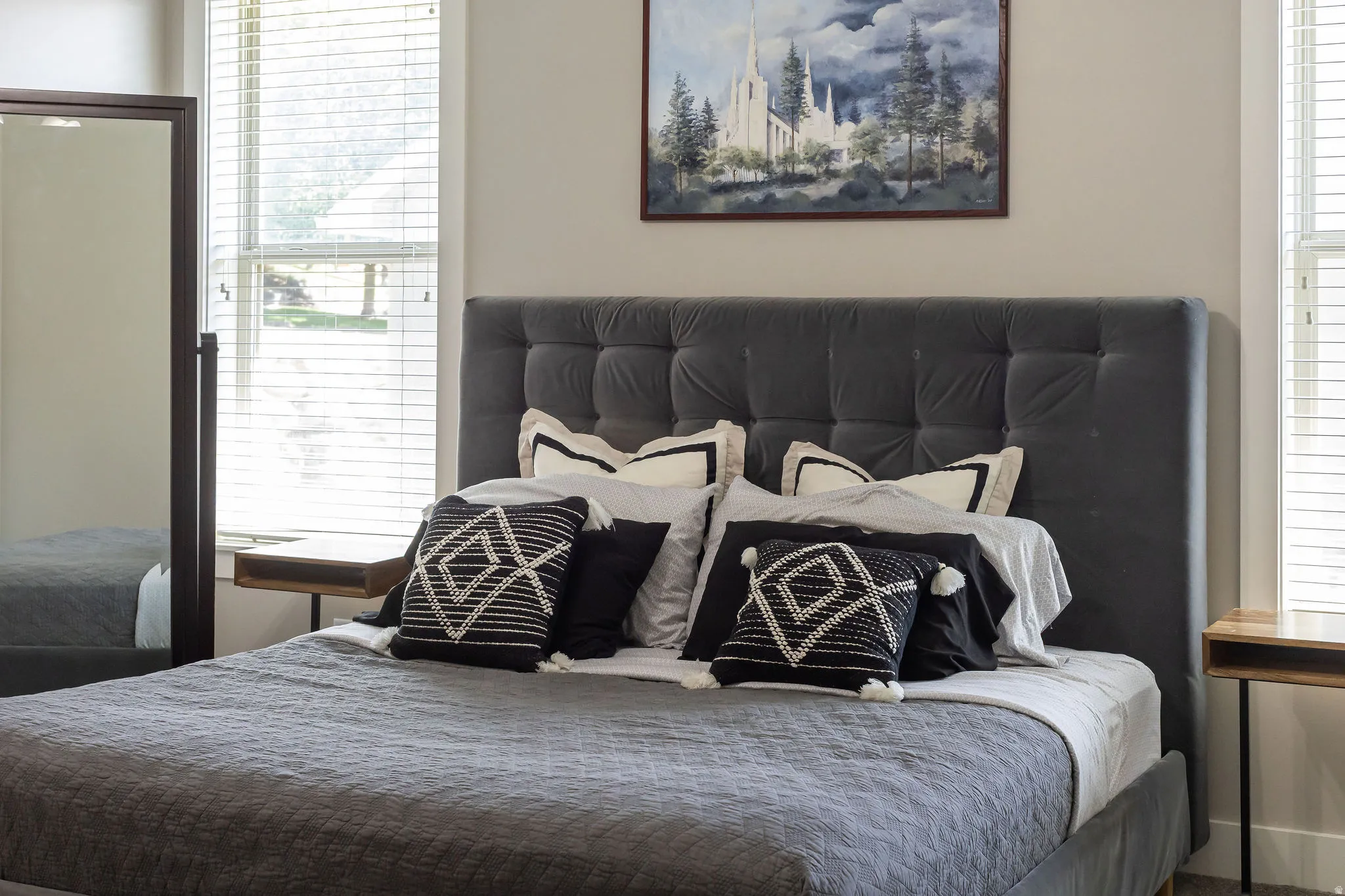 Bedroom featuring a tufted upholstered headboard, integrated wall-mounted nightstands, and window with blinds