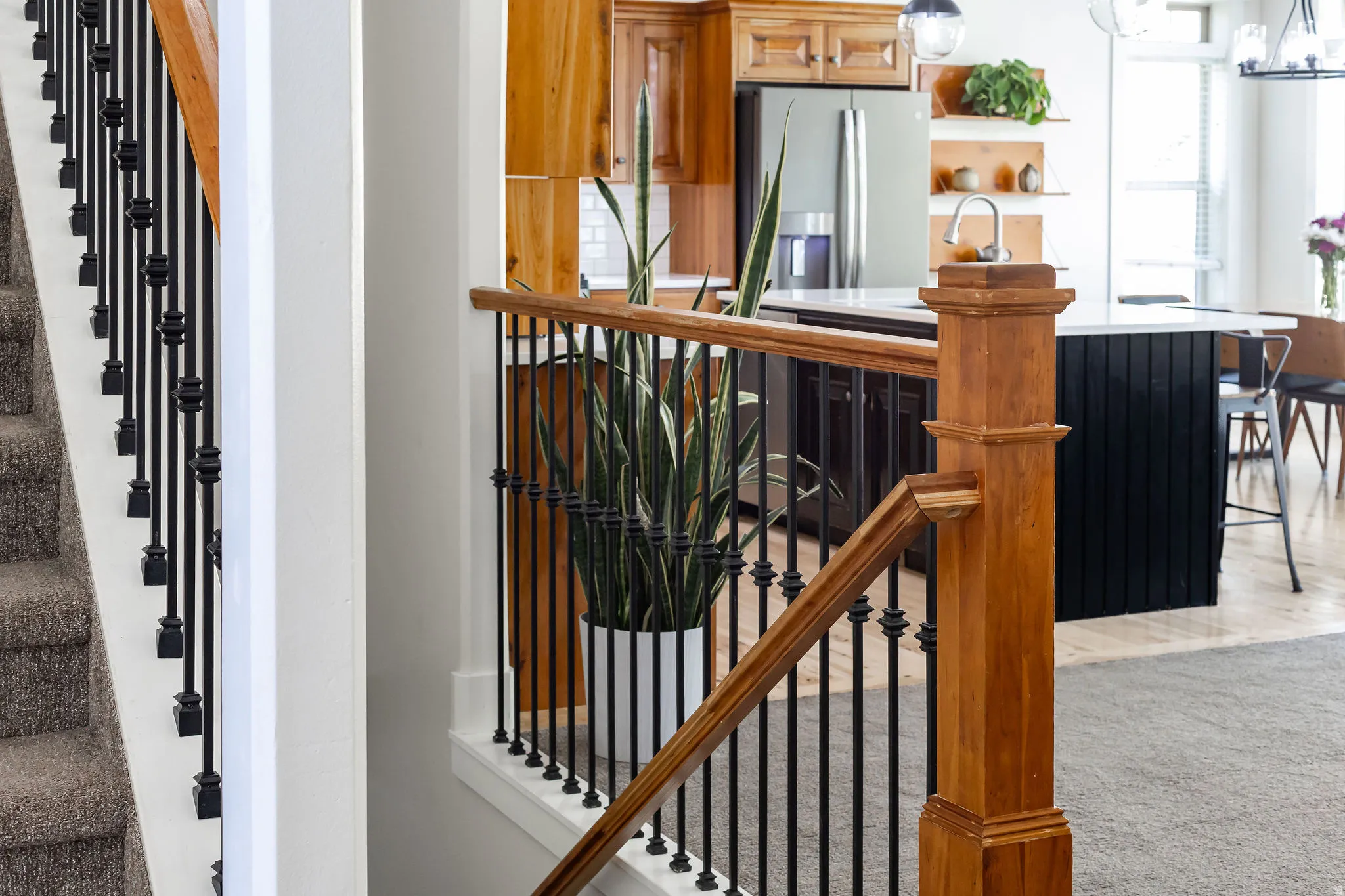 Staircase featuring wood handrails and black iron balusters