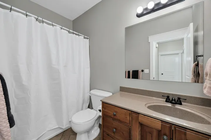 Bathroom featuring a wood vanity with a single basin sink, matte black fixtures, and a large mirror