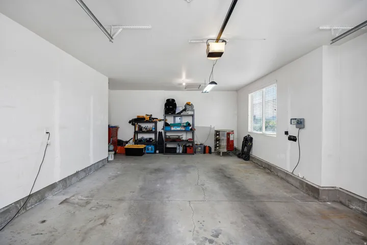 Spacious two-car garage featuring a concrete floor, white painted walls, and a window for natural light