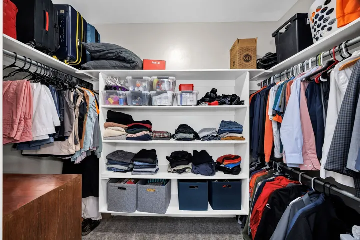 Walk-in closet featuring extensive built-in shelving, multiple hanging rods, and an integrated central storage unit