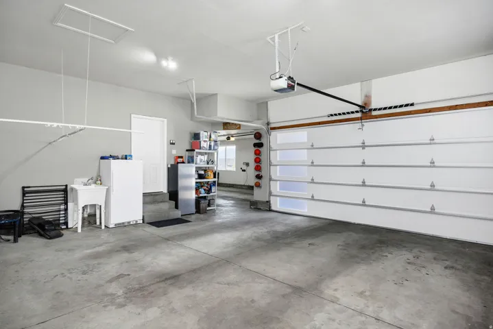 Spacious garage featuring a concrete floor, overhead door with translucent panels, and an automatic garage door opener