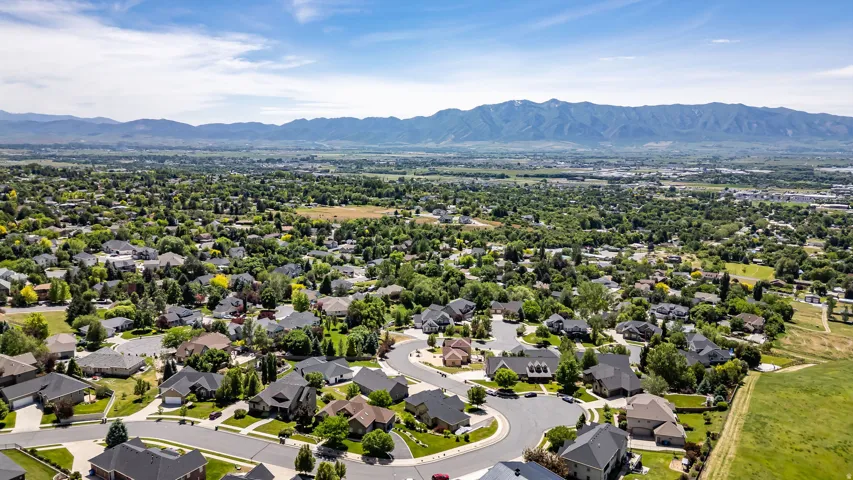Expansive suburban landscape featuring established residential properties with mature landscaping and mountain range backdrops