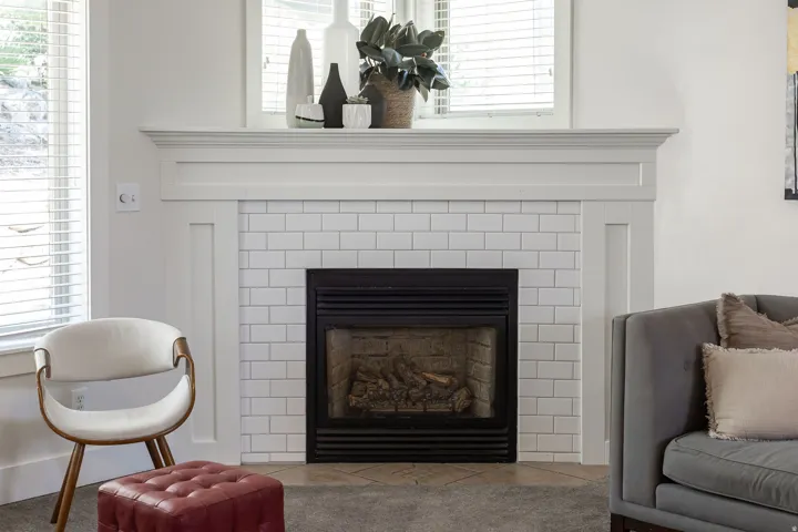 Fireplace featuring a white subway tile surround, a dark metal firebox, and a detailed white mantel