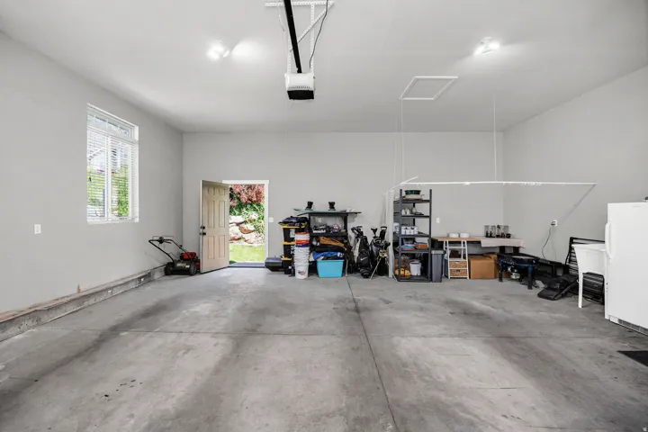 Spacious garage featuring a concrete floor, light gray walls, and a window with blinds