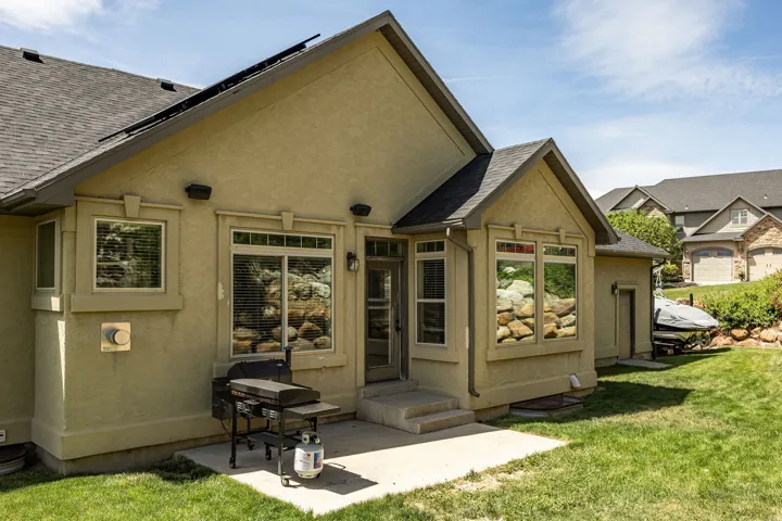 Stucco exterior with multiple windows and a shingled roof