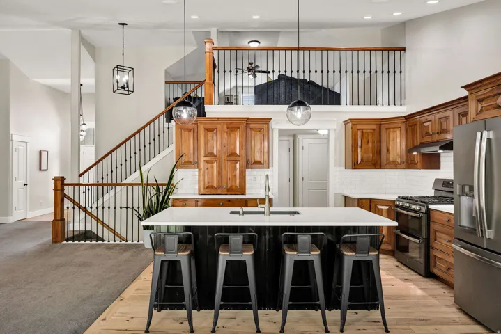 Open-concept kitchen featuring a spacious island with seating, stainless steel appliances, and wood cabinetry