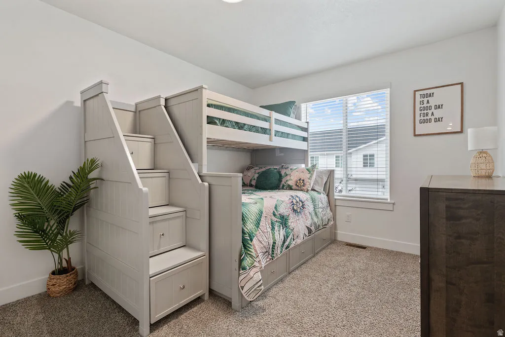Light gray bunk bed with integrated staircase storage, coordinating base bed drawers, and window with blinds
