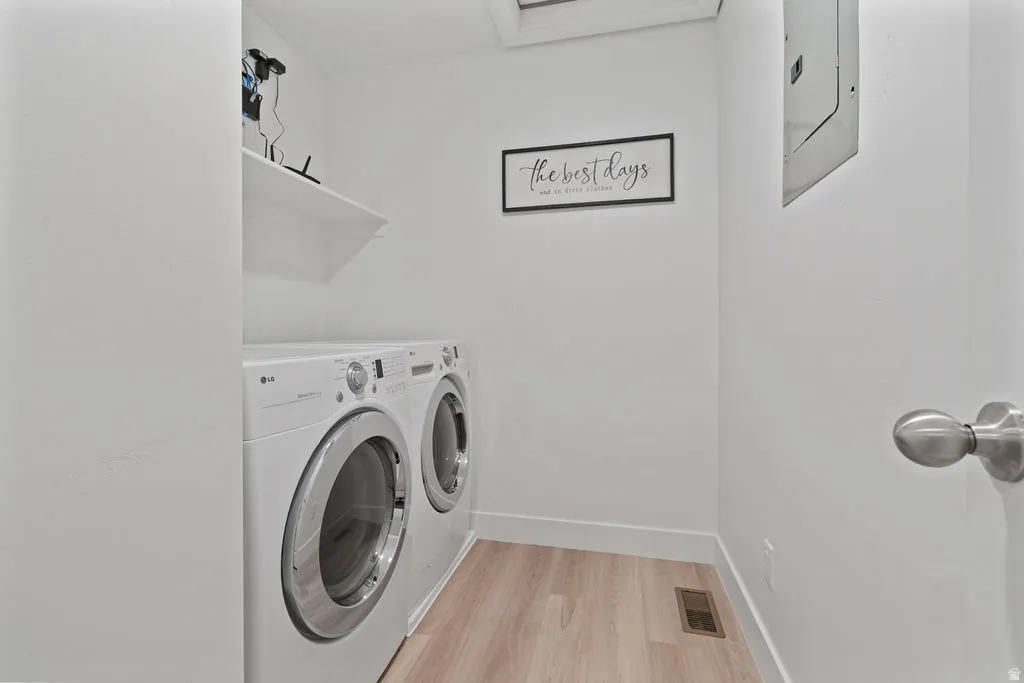 Dedicated laundry area featuring light wood-finish flooring, a wall-mounted shelf, and white baseboards