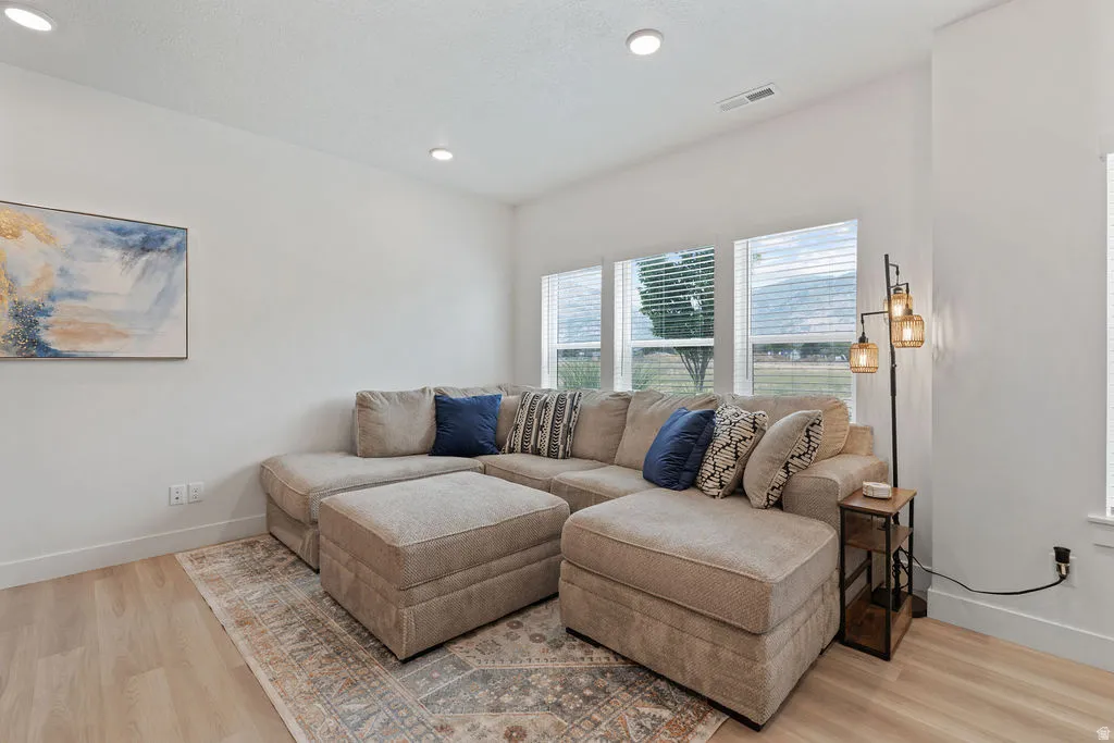 Bright living space featuring light wood-finish flooring, recessed lighting, and white walls
