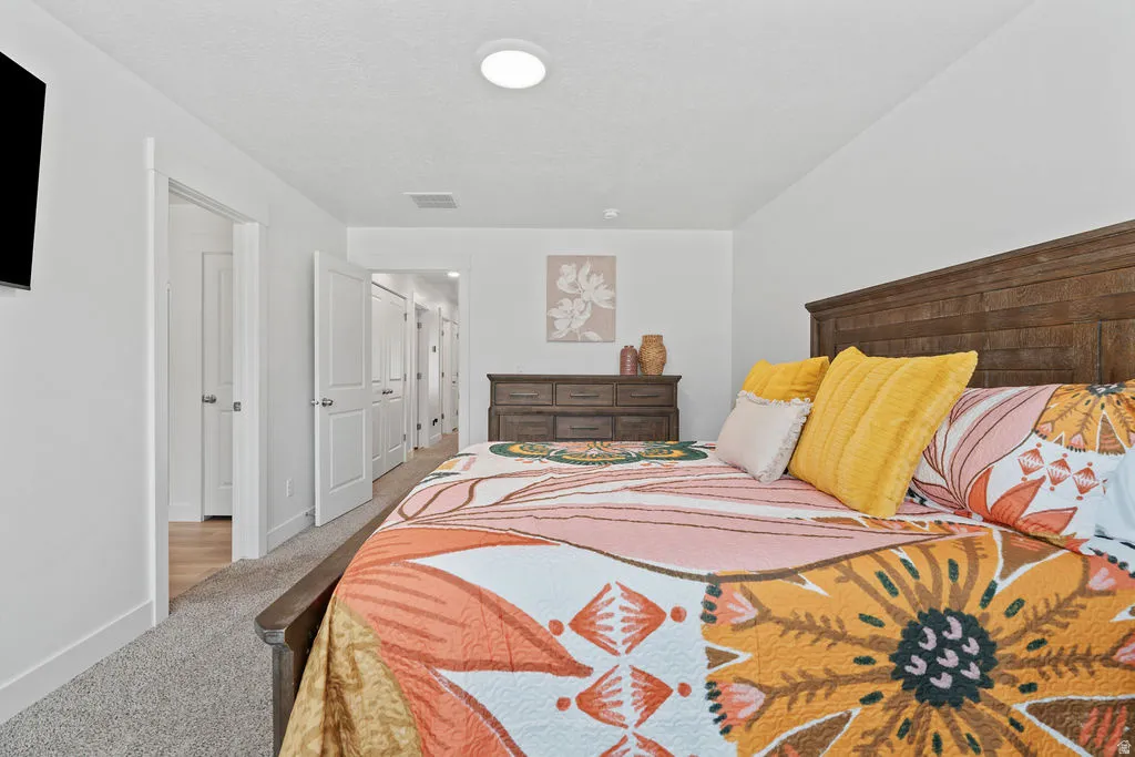 Spacious bedroom featuring light neutral walls and recessed lighting