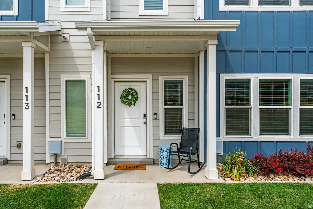 Entry features a covered porch with white columns, light gray siding, and a white front door