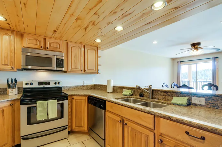 Kitchen featuring wood cabinetry, a double basin stainless steel sink, and light-toned countertops