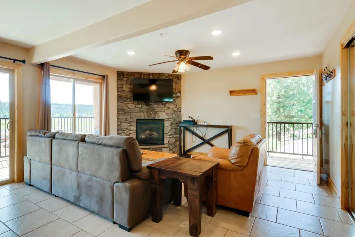 Living area featuring a stone-clad fireplace with a mounted television, a ceiling fan, recessed lighting, and tile flooring