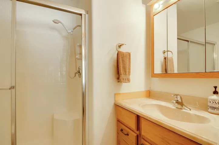 Bathroom featuring a vanity with wood-finish cabinetry, an integrated sink, and a framed medicine cabinet with overhead lighting