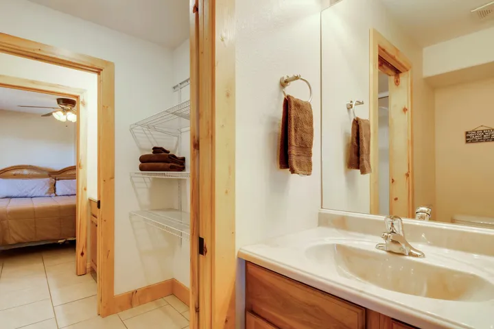 Bathroom vanity featuring an integrated sink with chrome faucet, a large wall-mounted mirror, and wood-finish cabinetry