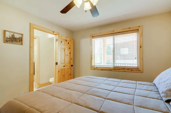 Interior room featuring natural wood trim, a window with blinds, a wood-finish interior door, and an overhead ceiling fan with light fixture