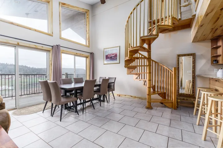 Expansive living space featuring a spiral staircase with wood newel posts and spindles, rectangular floor tiling, and a dining area with direct access to an outdoor balcony