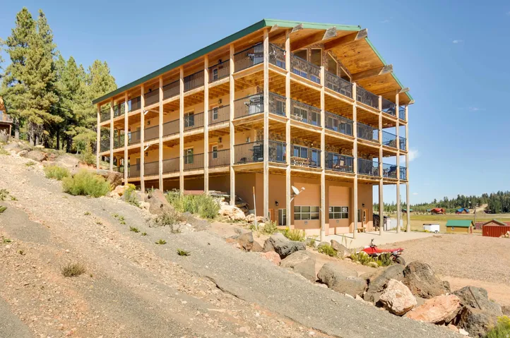 Multi-story property featuring extensive balconies with black metal railings, exposed wood framing, and a green metal roof
