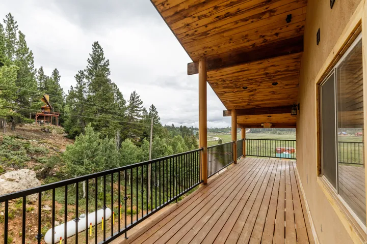 Expansive wood deck with black metal railings, a natural wood ceiling, and round support columns