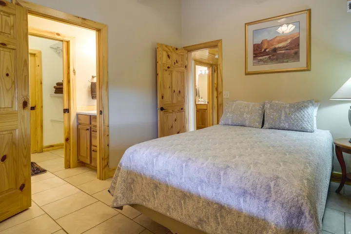 Bedroom featuring a light color palette, tile flooring, and natural wood trim and doors