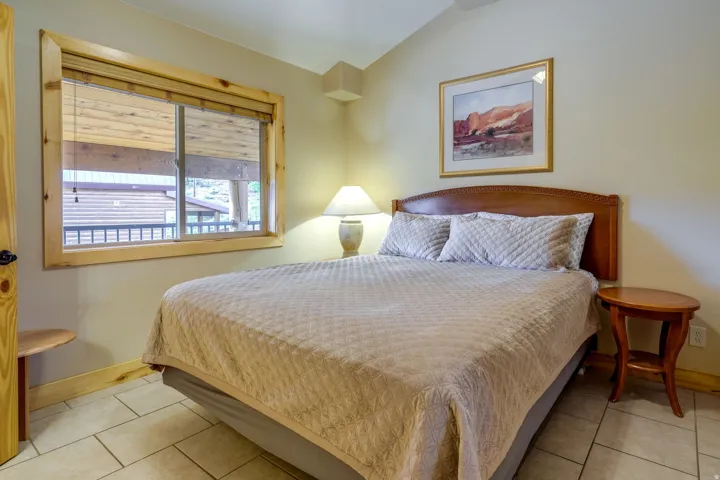 Bedroom featuring tile flooring, a window with wood trim, and a wood headboard