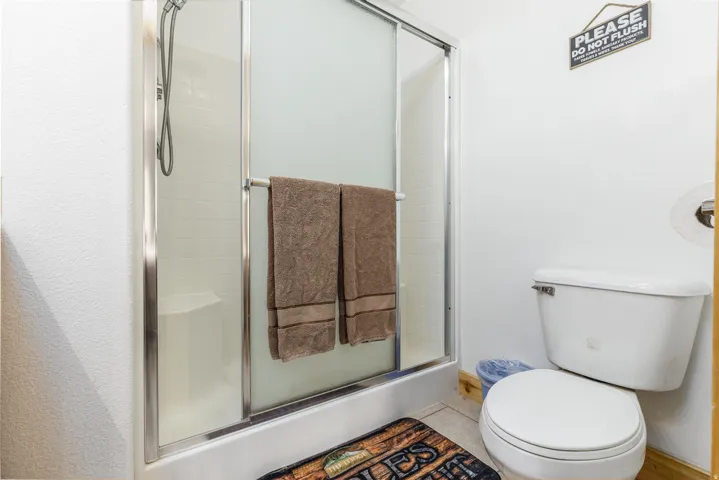 Bathroom featuring a shower with sliding glass doors, white tiled walls, and a built-in shower seat