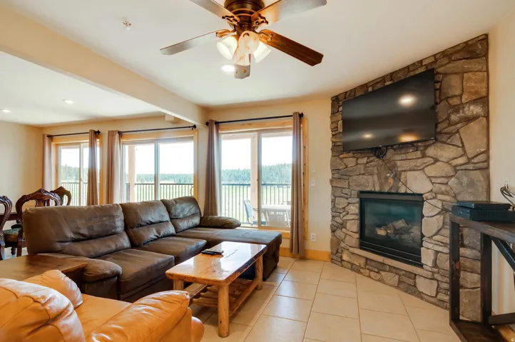 Great room featuring a natural stone fireplace with an integrated firebox, a ceiling fan with integrated lighting, recessed lighting, and multiple sliding glass doors opening to the outdoors