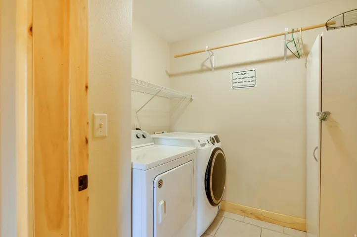 Laundry area featuring a side-by-side washer and dryer, tile flooring, and overhead shelving