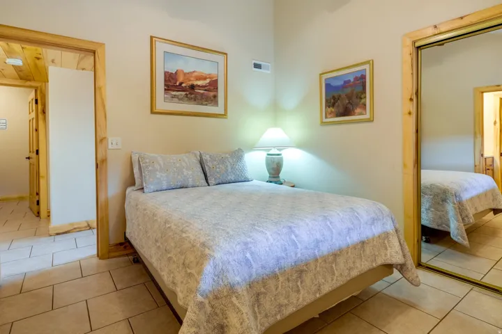 Interior room featuring light-toned walls, tile flooring, and natural wood trim around doorways and a mirrored closet door