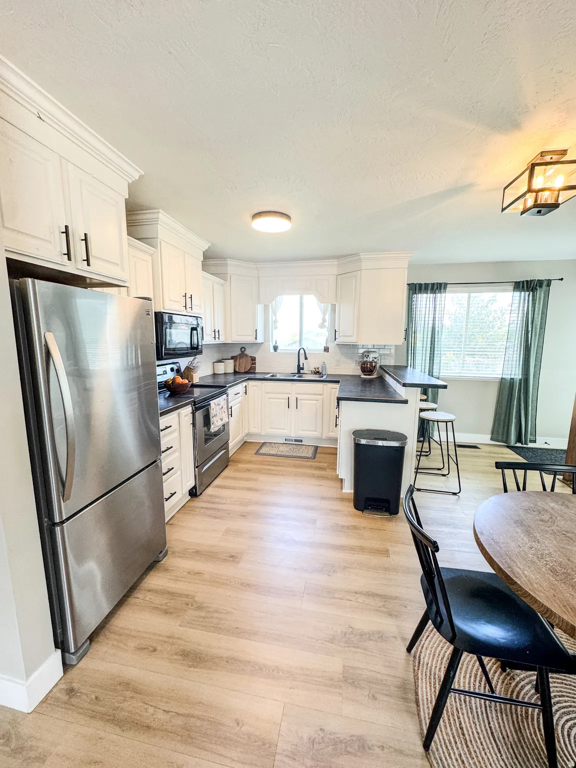 Kitchen featuring white cabinetry with dark hardware, dark countertops, and wood-finish flooring