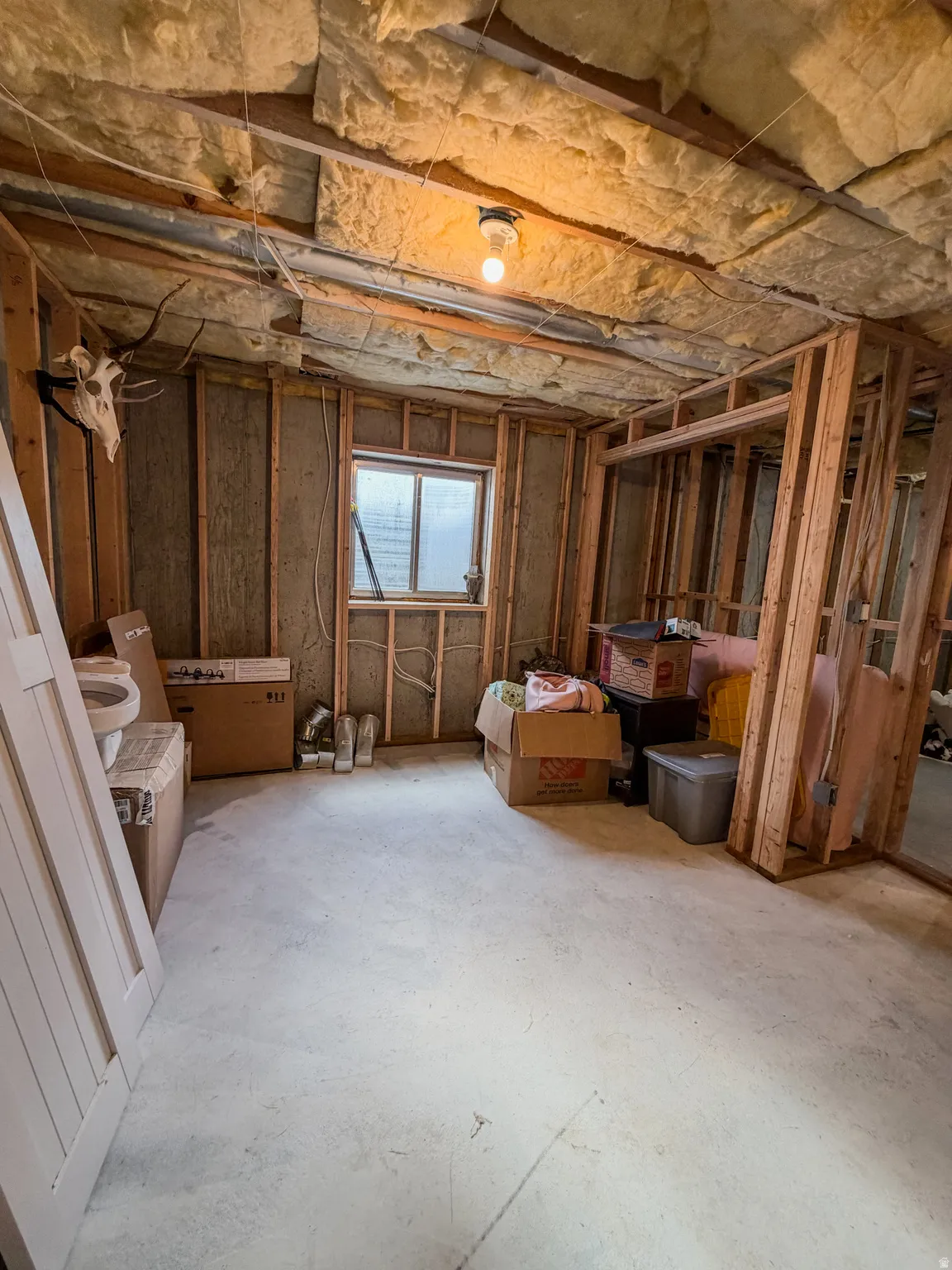 Unfinished interior space featuring exposed wood framing, ceiling insulation, and a concrete floor