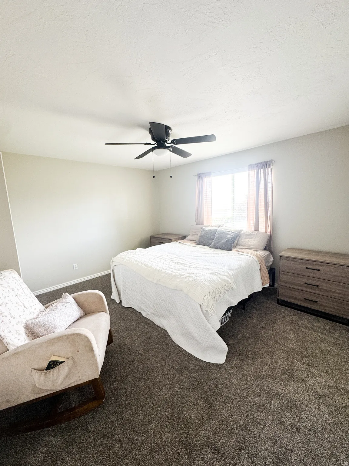 Carpeted room featuring a ceiling fan with integrated lighting, neutral wall tones, and a window with blinds