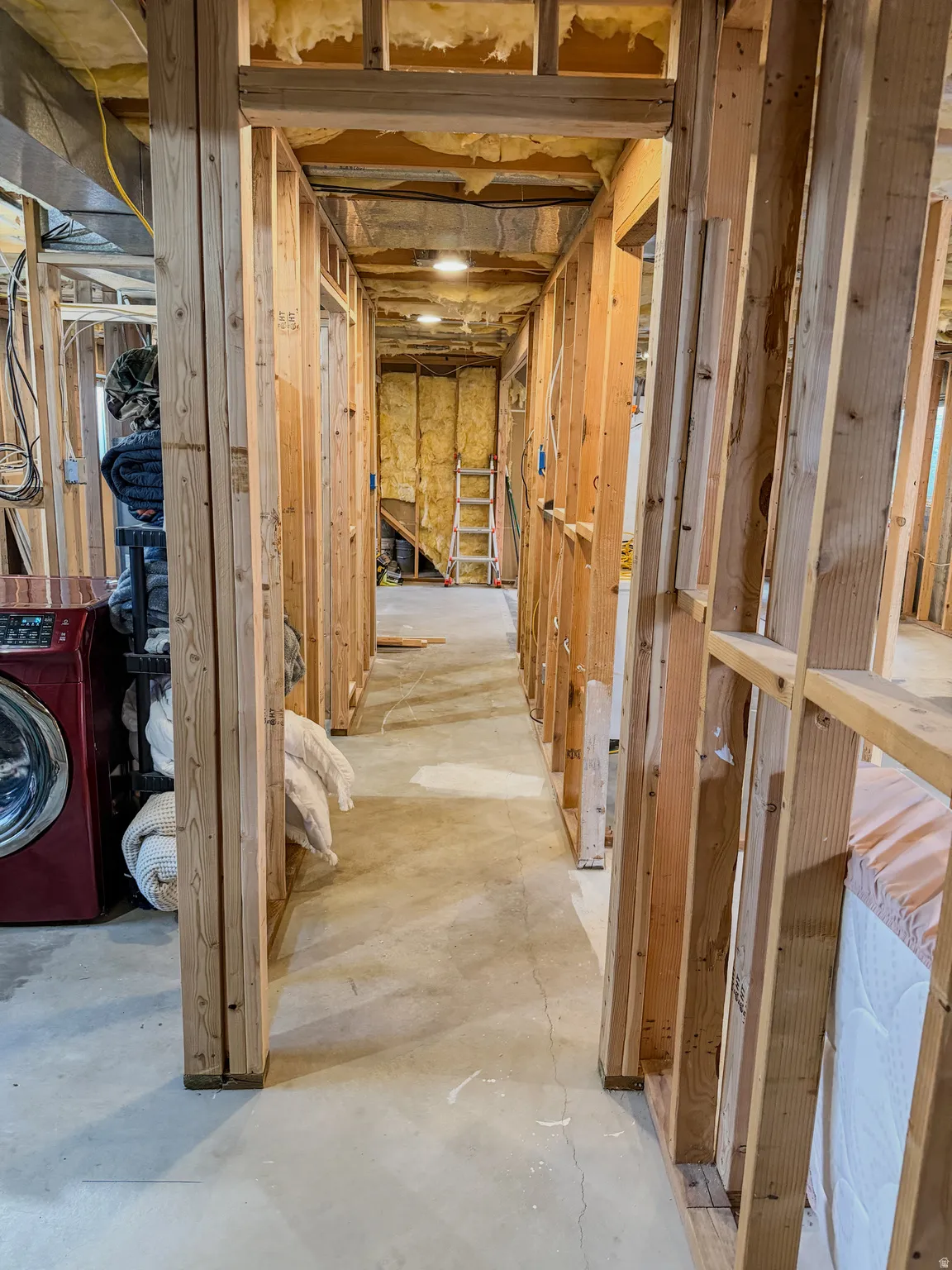 Framed interior space with exposed wooden studs, concrete flooring, and visible insulation