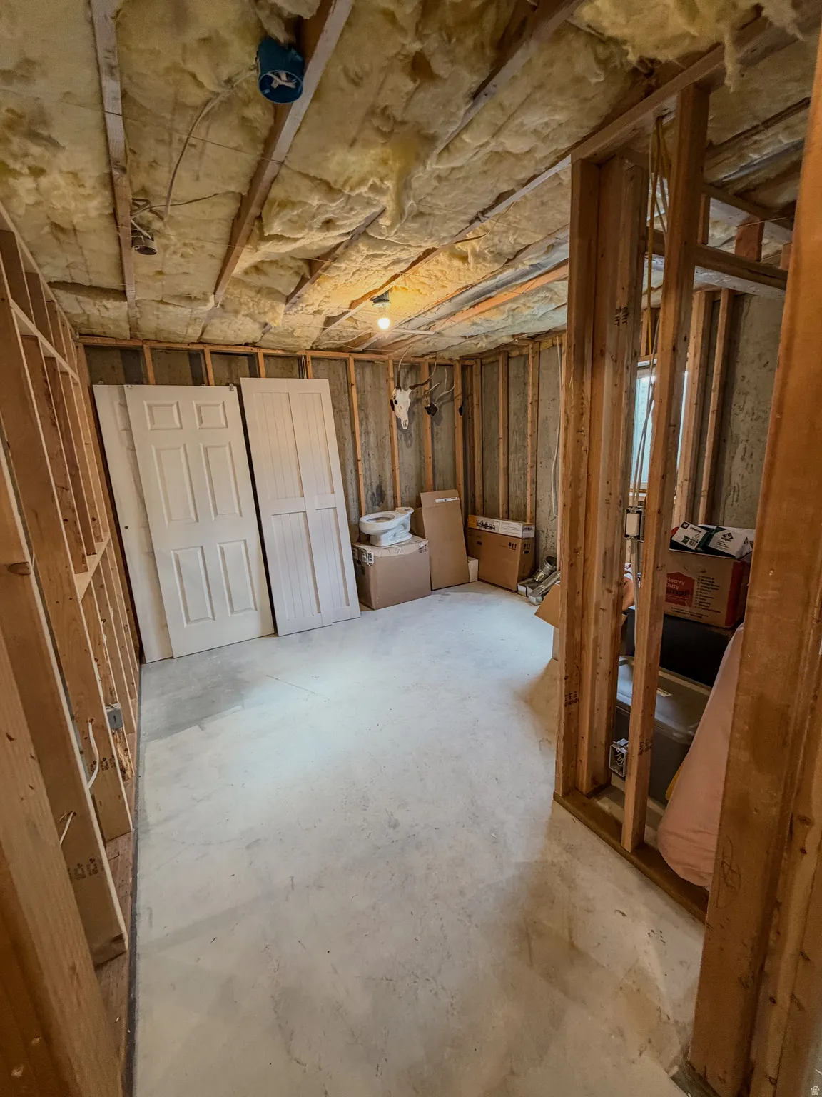 Unfinished interior space featuring exposed wood framing, ceiling insulation, and a concrete floor