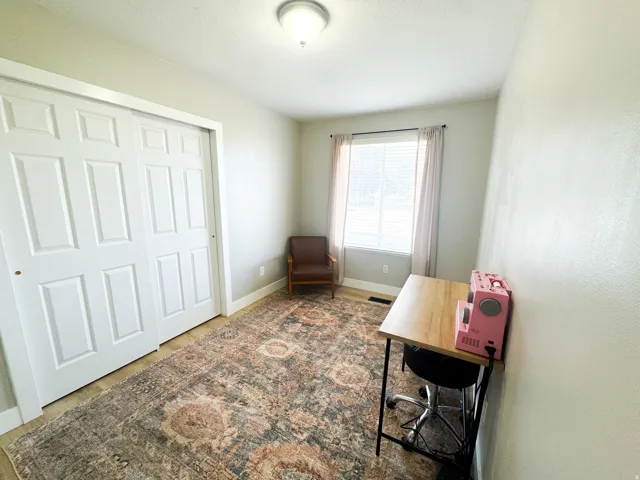 Room featuring wood-finish flooring, a double-door closet with paneled doors, and a window with blinds