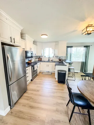 Kitchen featuring white cabinetry with dark hardware, dark countertops, and wood-finish flooring