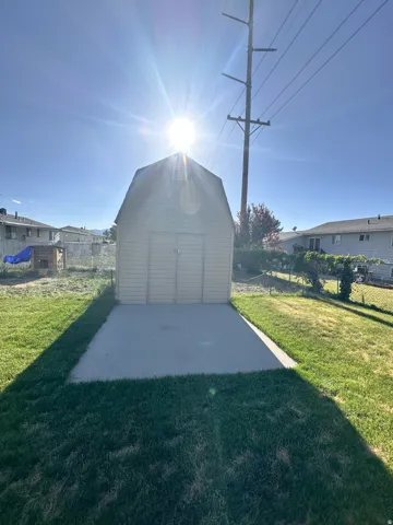 Gabled storage shed with double doors, set on a concrete slab, surrounded by a grassy yard
