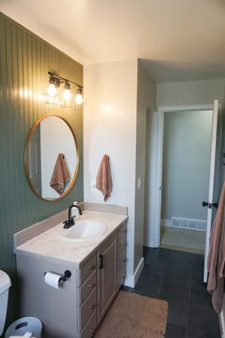 Bathroom featuring a single vanity with an integrated sink, black matte faucet, and ample storage
