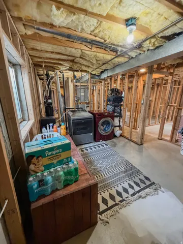 Unfinished basement space featuring exposed wooden framing, visible insulation, and concrete flooring