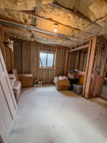 Unfinished interior space featuring exposed wood framing, ceiling insulation, and a concrete floor