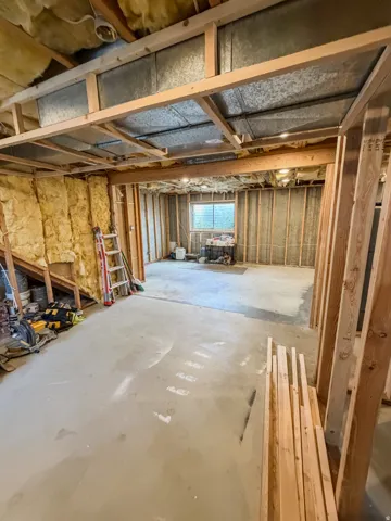Unfinished lower level featuring exposed framing, concrete flooring, and a visible window opening